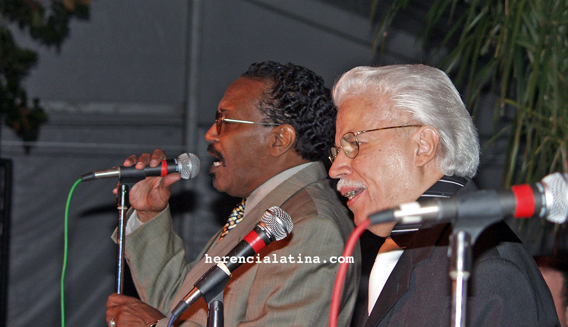 Ambos en la tarima del escenario Héctor Casanova Pagán cantando y Johnny Pacheco en coros