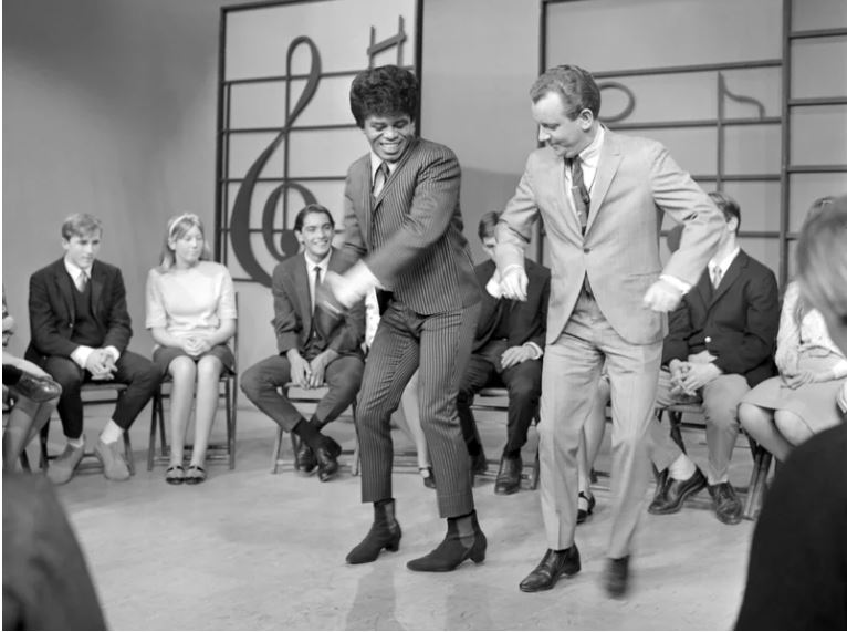 James Brown se presenta en los estudios KCOP en el Show de Lloyd Thaxton con el mismo Lloyd Thaxton en 1964. Brown ayudó a popularizar el baile al estilo boogaloo, que se muestra aquí.  Archivos de Michael Ochs / Getty Images
